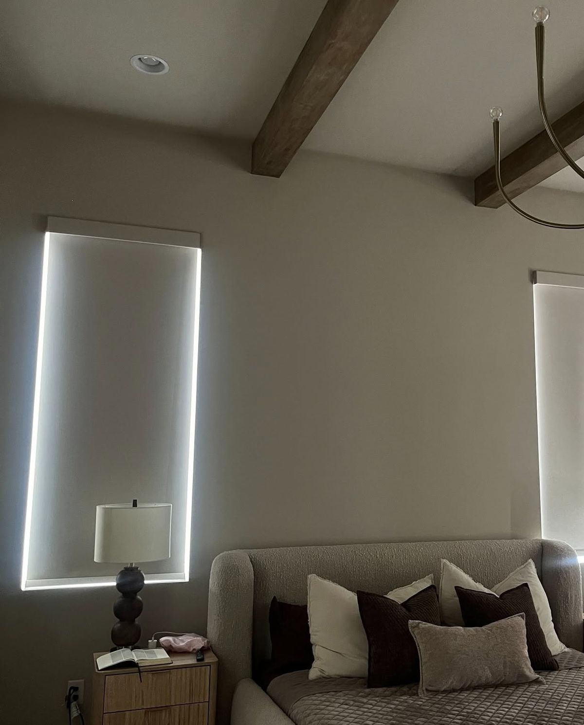 A bedroom window with a Brentwood Blind Company shade installed, daylight glowing around its edges